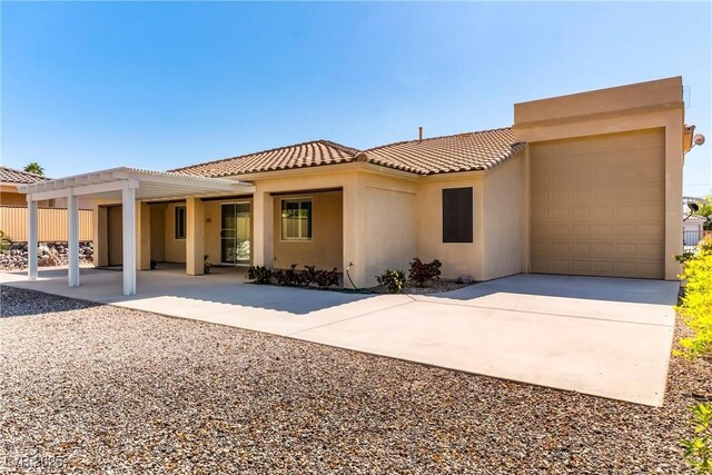 rear view of house with stucco siding, driveway, and a garage