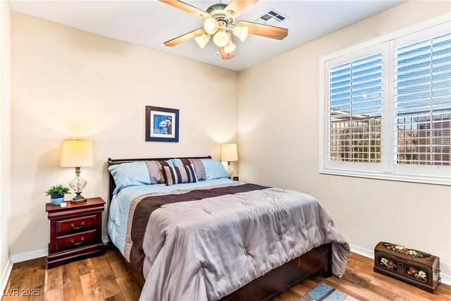 bedroom with wood finished floors, visible vents, baseboards, and ceiling fan