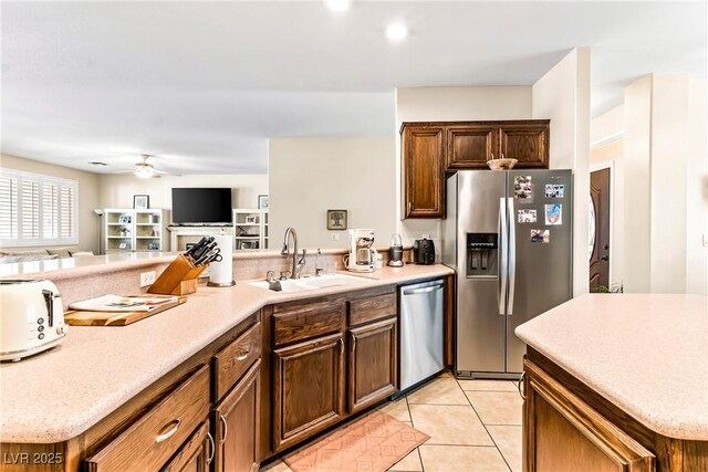 kitchen featuring stainless steel appliances, light countertops, open floor plan, and a sink