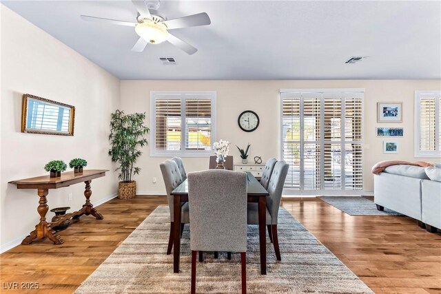 dining room with baseboards, wood finished floors, visible vents, and a ceiling fan