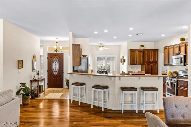 kitchen with a kitchen bar, appliances with stainless steel finishes, and wood finished floors