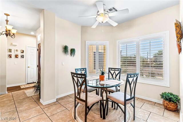 dining space with baseboards, ceiling fan with notable chandelier, visible vents, and light tile patterned floors