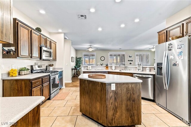 kitchen with stainless steel appliances, a center island, ceiling fan, and light tile patterned flooring