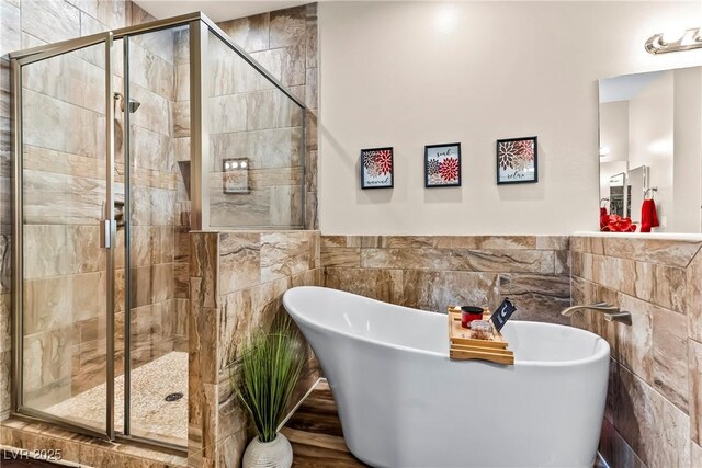full bath with tile walls, wainscoting, a freestanding bath, and a stall shower