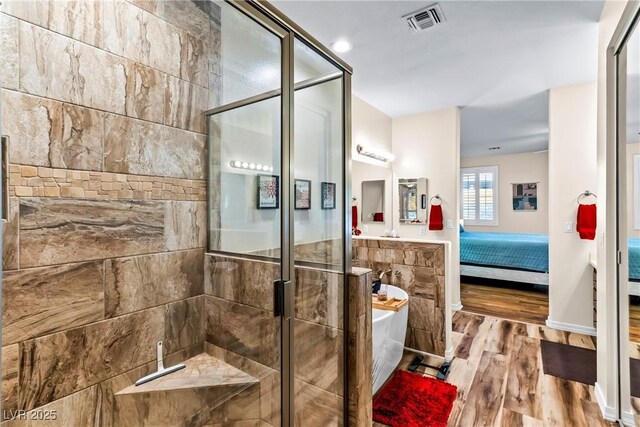 full bathroom featuring wood finished floors, a stall shower, connected bathroom, a soaking tub, and visible vents