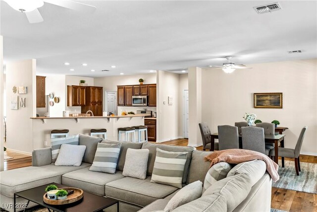 living room featuring a ceiling fan, wood finished floors, visible vents, and recessed lighting