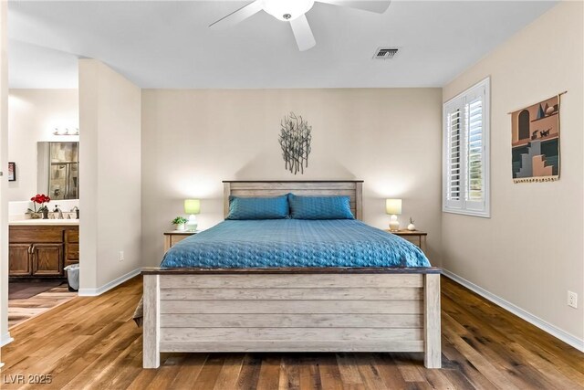 bedroom featuring connected bathroom, baseboards, wood finished floors, and visible vents