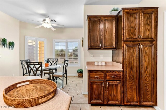 kitchen featuring light countertops, dark brown cabinets, ceiling fan, and light tile patterned floors