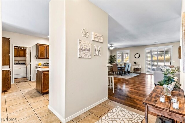 hallway with light tile patterned flooring, baseboards, and washer / clothes dryer