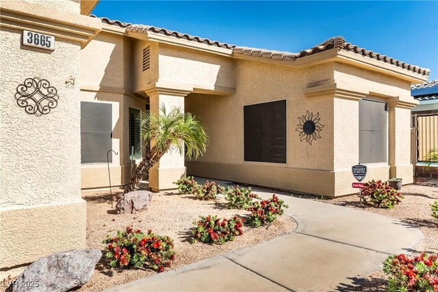 doorway to property featuring a tile roof and stucco siding