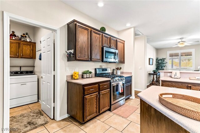kitchen featuring stainless steel appliances, light tile patterned flooring, ceiling fan, light countertops, and washer / dryer