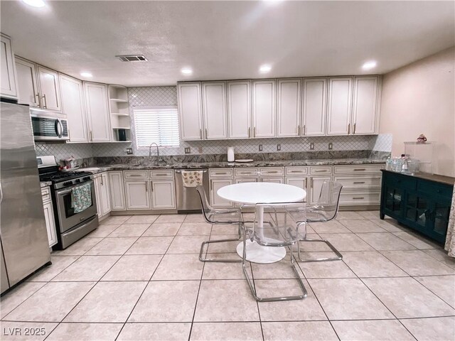 kitchen with a sink, open shelves, appliances with stainless steel finishes, and light tile patterned floors