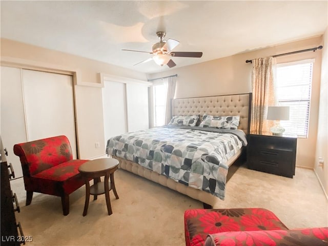 bedroom with multiple closets, a ceiling fan, and light carpet