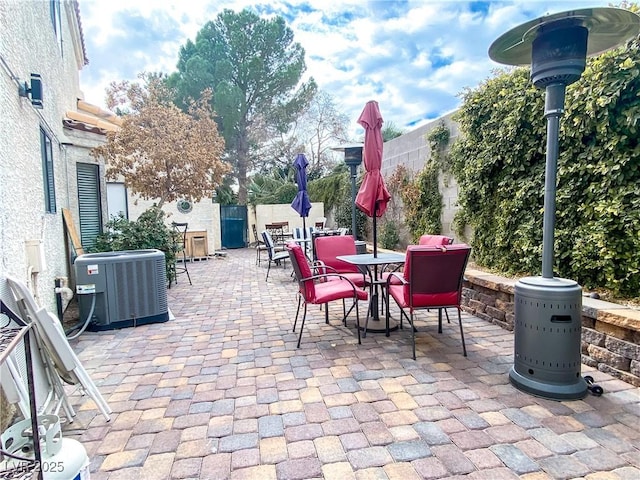 view of patio with outdoor dining area, central AC, and a fenced backyard