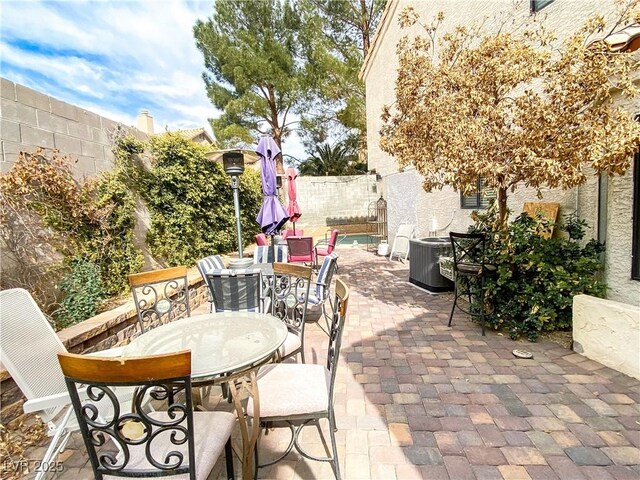 view of patio with a fenced backyard, outdoor dining space, and central air condition unit