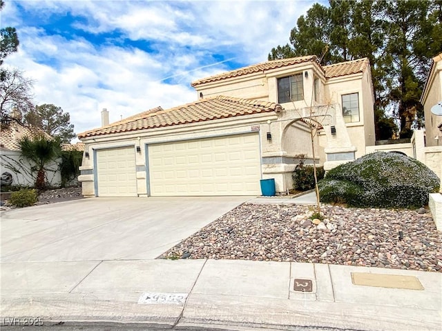 mediterranean / spanish home featuring a tiled roof, a garage, stucco siding, and concrete driveway