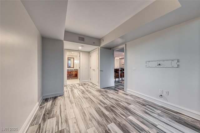 unfurnished living room featuring baseboards, wood finished floors, and visible vents