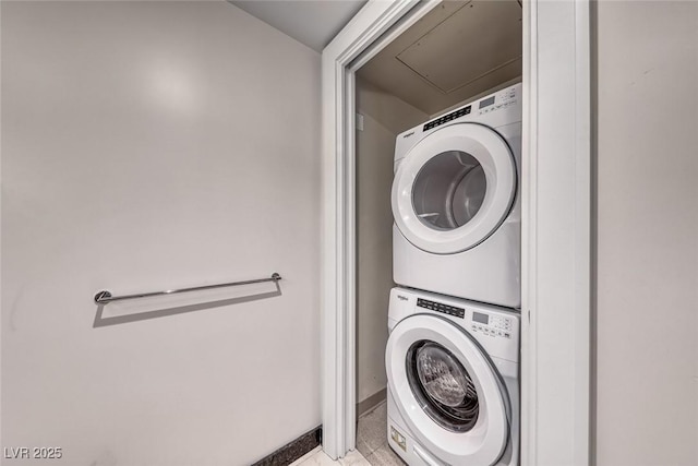 washroom with baseboards, stacked washer and clothes dryer, light tile patterned flooring, and laundry area