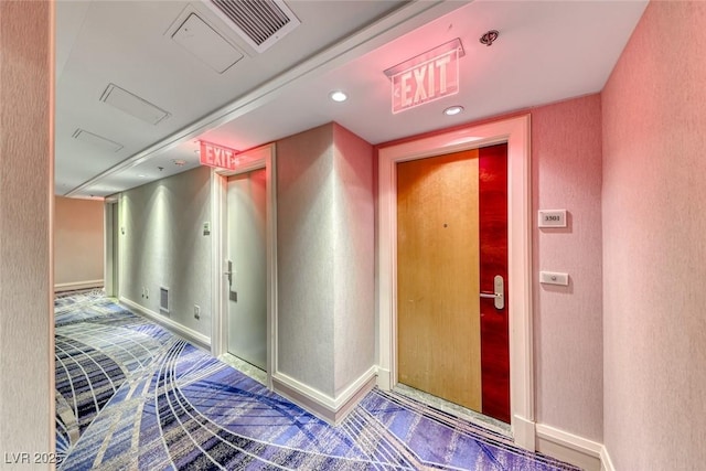 hall with baseboards, visible vents, and a textured wall