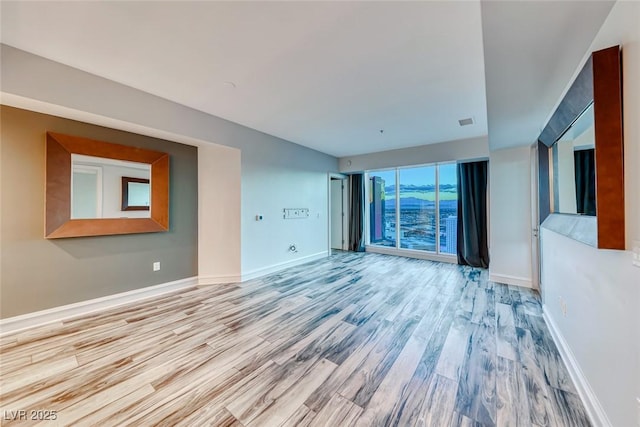 unfurnished living room with baseboards, wood finished floors, and visible vents