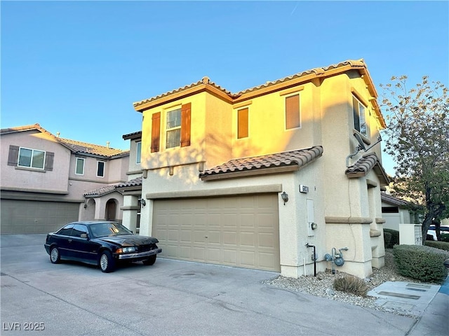 mediterranean / spanish house with a garage, stucco siding, concrete driveway, and a tile roof