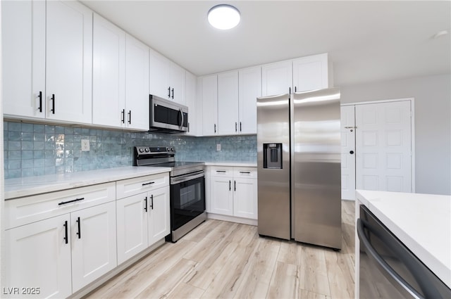 kitchen with light wood-style flooring, light countertops, backsplash, white cabinetry, and stainless steel appliances