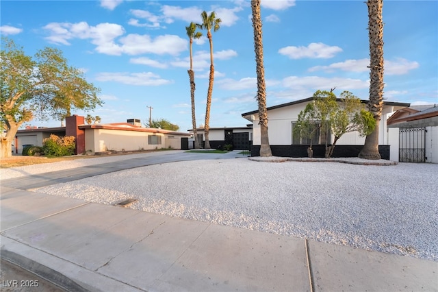 view of front of home with stucco siding, fence, and a gate