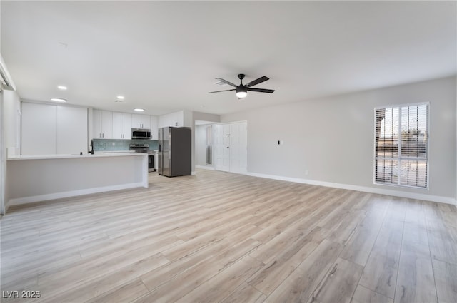 unfurnished living room featuring baseboards, a sink, a ceiling fan, recessed lighting, and light wood finished floors