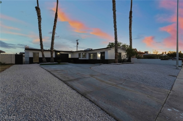 view of front facade with driveway, stucco siding, fence, and a gate