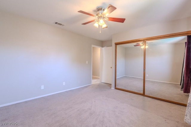 unfurnished bedroom featuring carpet flooring, a closet, visible vents, baseboards, and ceiling fan
