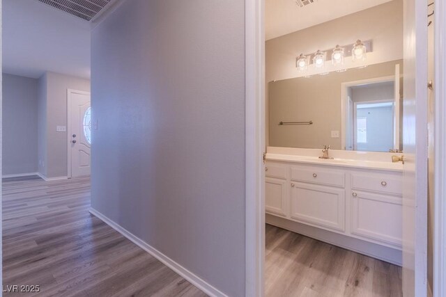 bathroom featuring vanity, visible vents, wood finished floors, and baseboards