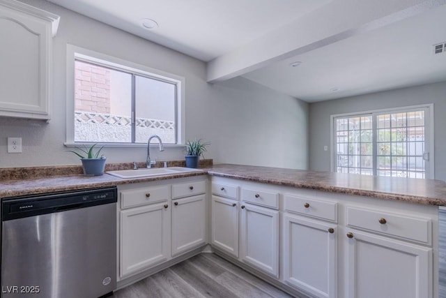 kitchen with a sink, a peninsula, light wood-type flooring, white cabinetry, and stainless steel dishwasher