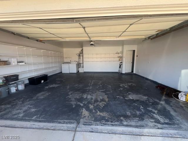 garage featuring washing machine and dryer, strapped water heater, and a garage door opener