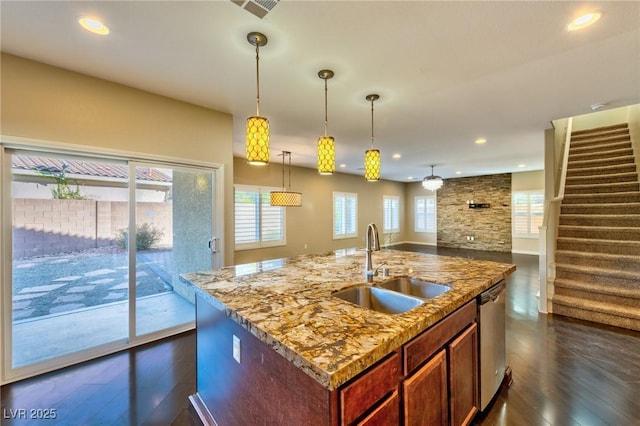 kitchen featuring stainless steel dishwasher, a sink, light stone countertops, and a wealth of natural light