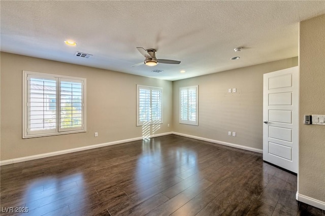 empty room featuring visible vents, dark wood-style flooring, a textured ceiling, and ceiling fan