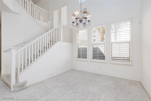 interior space featuring carpet flooring, a notable chandelier, and stairs