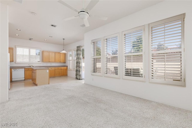 kitchen featuring light brown cabinets, visible vents, dishwasher, light colored carpet, and a sink