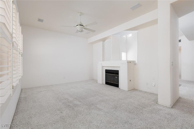unfurnished living room featuring carpet floors, a ceiling fan, and a glass covered fireplace