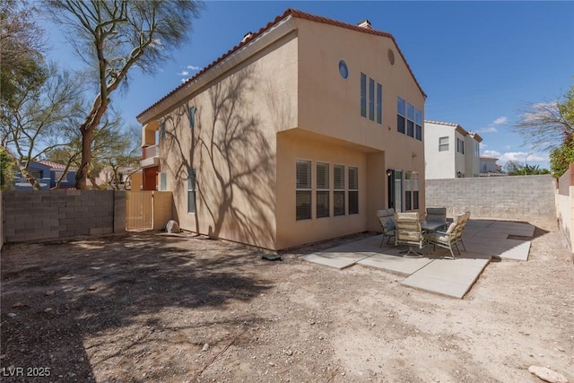 back of house featuring a patio area, a tile roof, fence private yard, and stucco siding