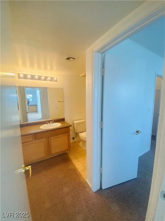 bathroom featuring toilet, vanity, and visible vents
