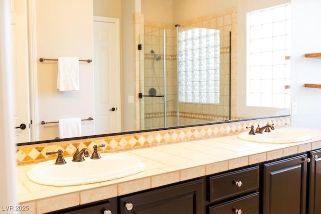 full bathroom with double vanity, a shower stall, and a sink