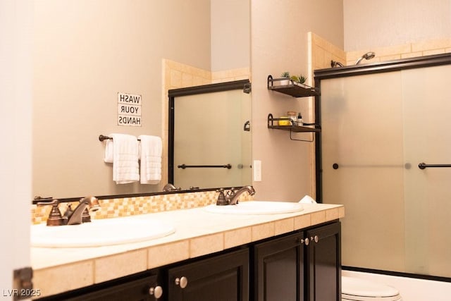 bathroom featuring an enclosed shower, a sink, double vanity, and toilet