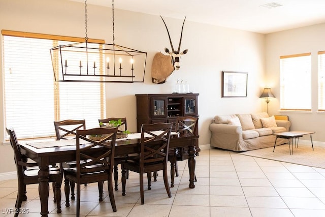 dining space featuring light tile patterned floors, baseboards, visible vents, and an inviting chandelier