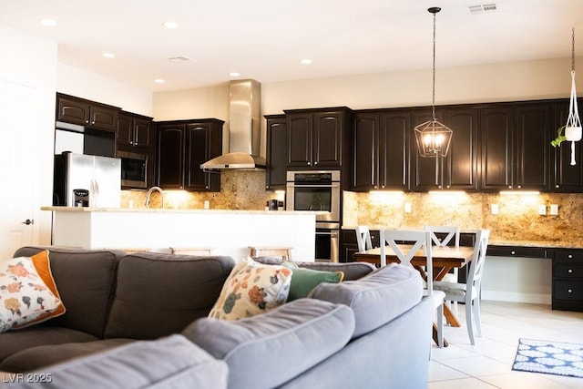 kitchen with wall chimney exhaust hood, appliances with stainless steel finishes, open floor plan, and light tile patterned floors