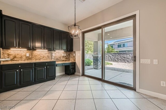 3908 Specula Wing Dr, North Las Vegas, NV 89084 - kitchen with decorative backsplash, light stone countertops, a chandelier, pendant lighting, and dark cabinetry