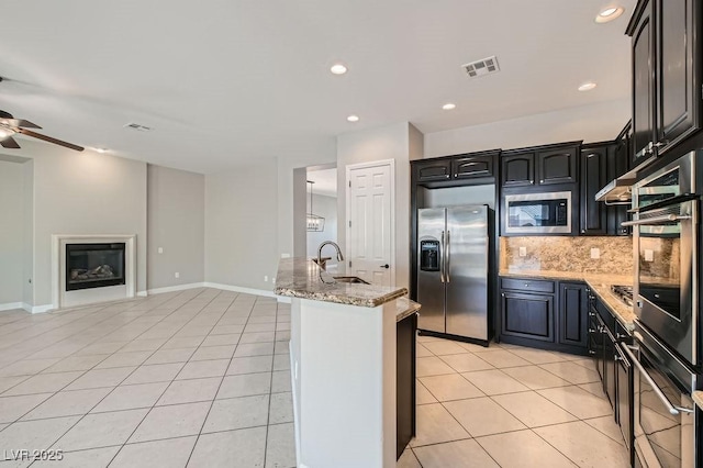 3908 Specula Wing Dr, North Las Vegas, NV 89084 - kitchen featuring appliances with stainless steel finishes, a ceiling fan, light tile patterned floors, backsplash, and light stone counters