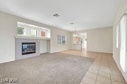 unfurnished living room with a glass covered fireplace and tile patterned flooring