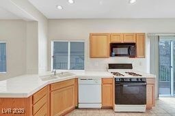 kitchen featuring recessed lighting, white appliances, light countertops, and a sink