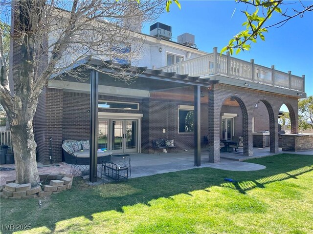 8690 W Ford Ave, Las Vegas, NV 89148 - back of house featuring french doors, brick siding, a balcony, a lawn, and a patio area