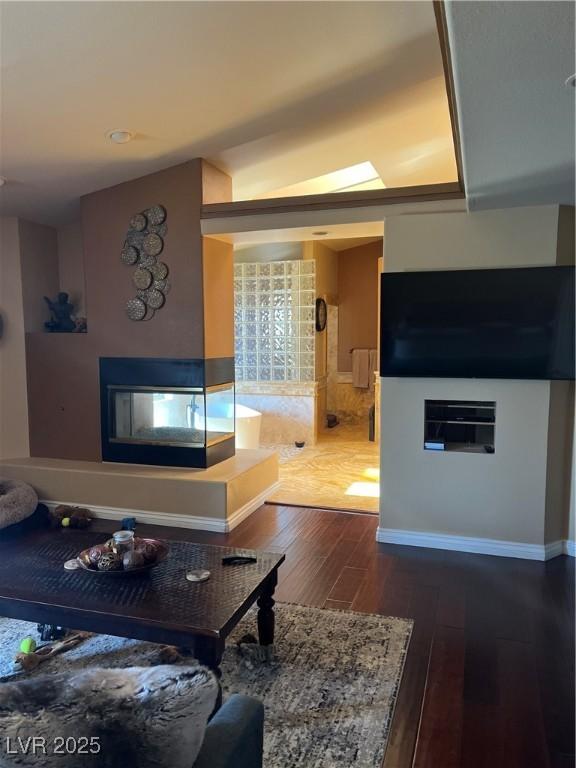 8690 W Ford Ave, Las Vegas, NV 89148 - living room featuring dark wood finished floors, a multi sided fireplace, and baseboards